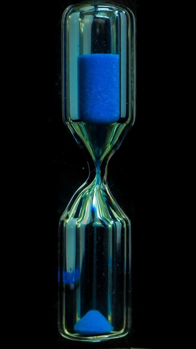 Hourglass with blue sand on a black background